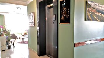A hallway with a door leading to a room, a framed picture on the wall, and a potted plant.