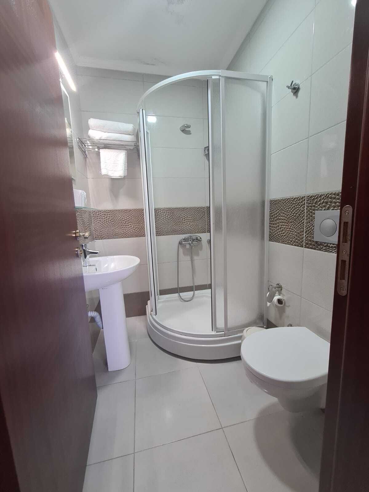A modern bathroom with a glass-enclosed shower, a white sink, and a toilet.