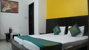 Habitación de hotel con una cama grande, una silla, una mesita y un cuadro colgado en la pared.