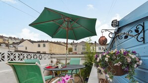 Un patio con una mesa, sillas y una cesta de flores colgante.