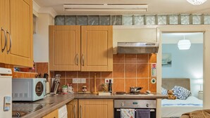 Una cocina compacta con armarios de madera, un microondas, una estufa y una lavadora.