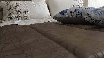 A bed with a brown patterned bedspread and decorative pillows with floral designs.