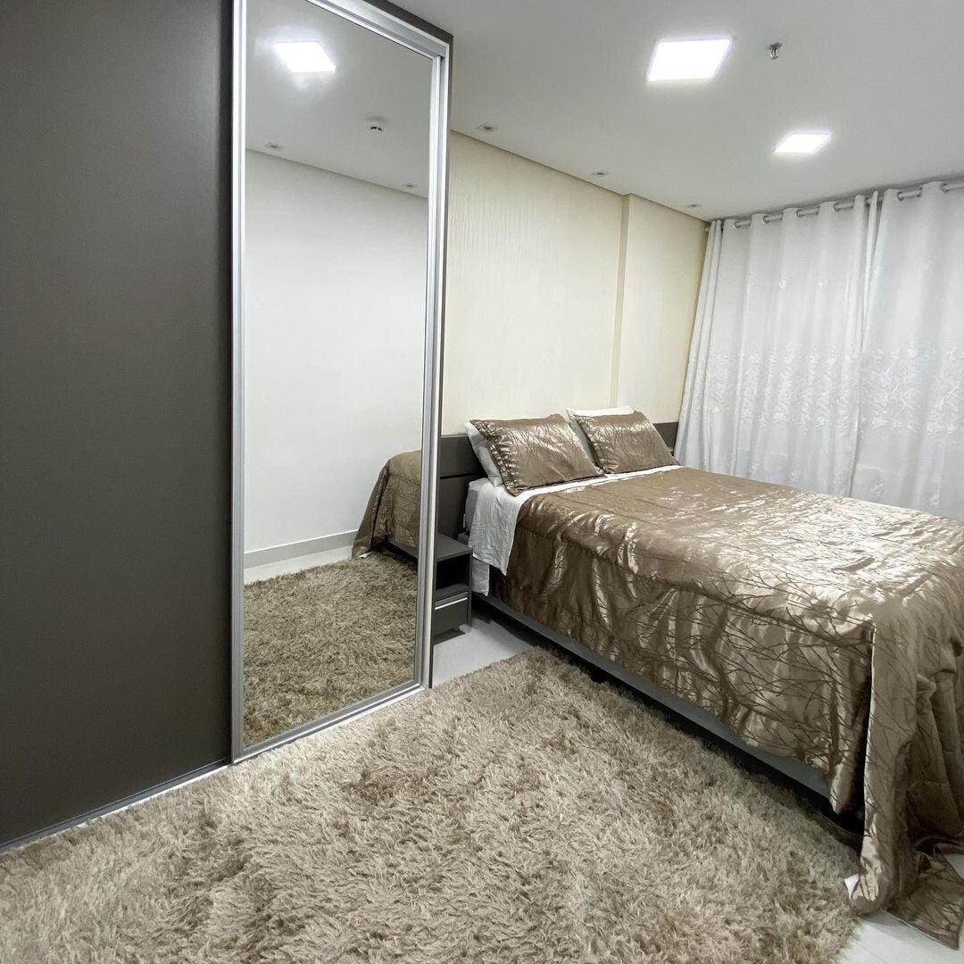 Une chambre à coucher avec un lit, un miroir et un sol recouvert de moquette.