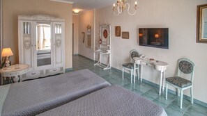 A hotel room with a bed, a vanity, a television, and a seating area with chairs.