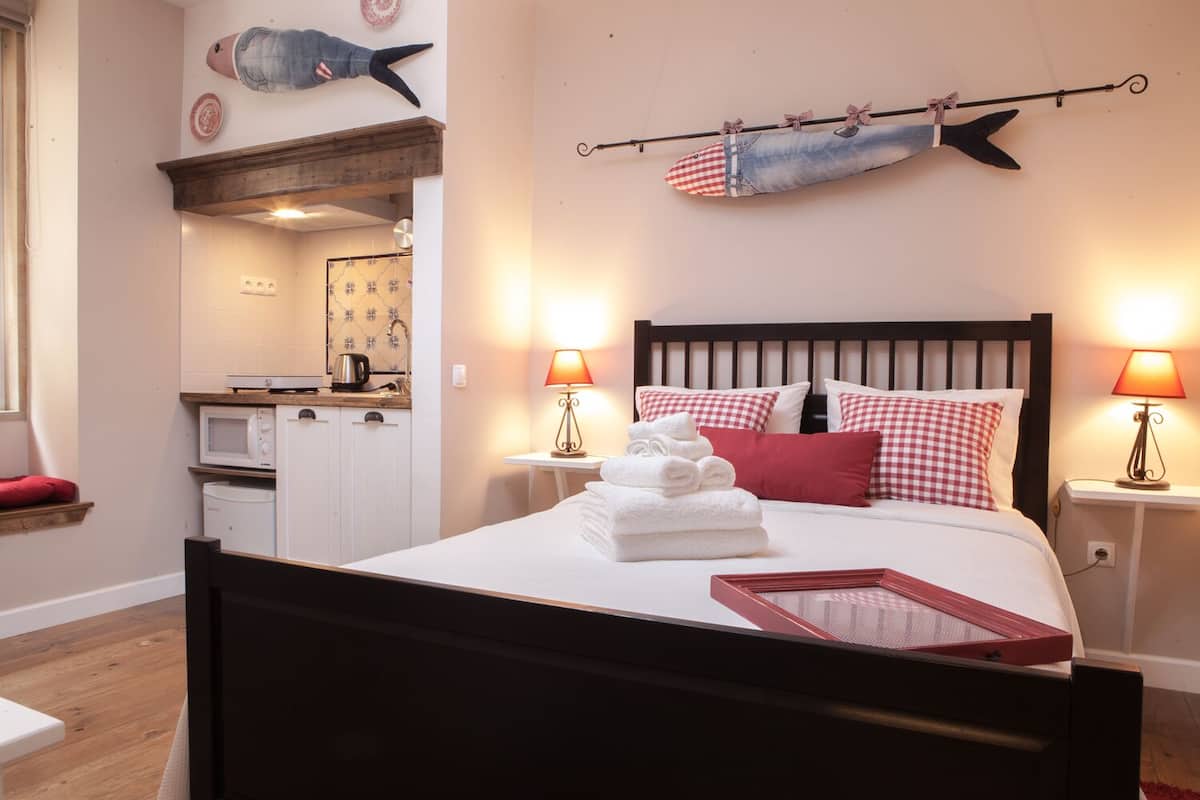 A neatly arranged bedroom with a bed, bedside lamps, and a wall-mounted fish decoration.