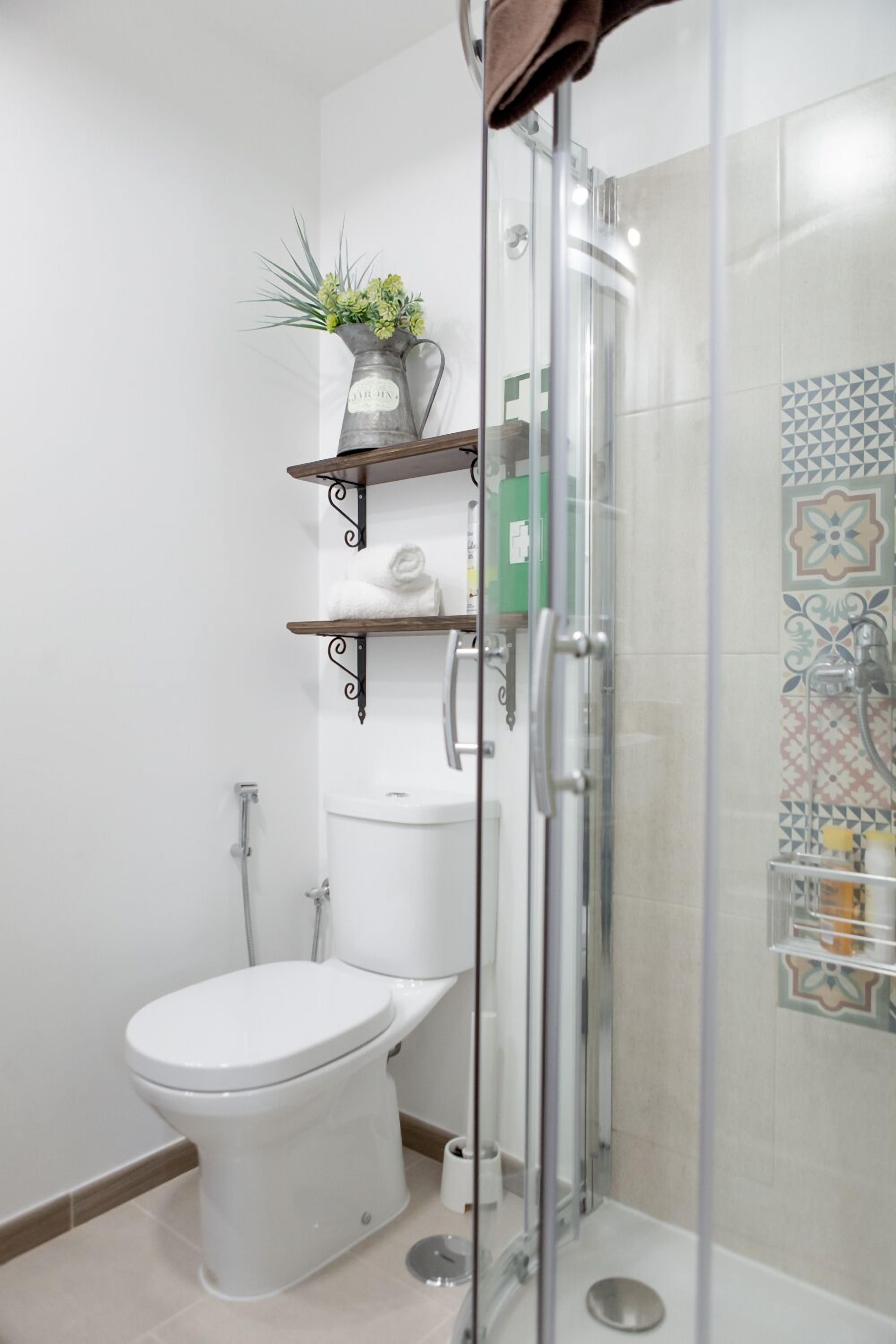 Un baño moderno con cabina de ducha de vidrio, inodoro y lavabo.