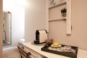 Une cuisine équipée d’une machine à café, d’un plateau avec des tasses et d’une étagère avec des plantes.