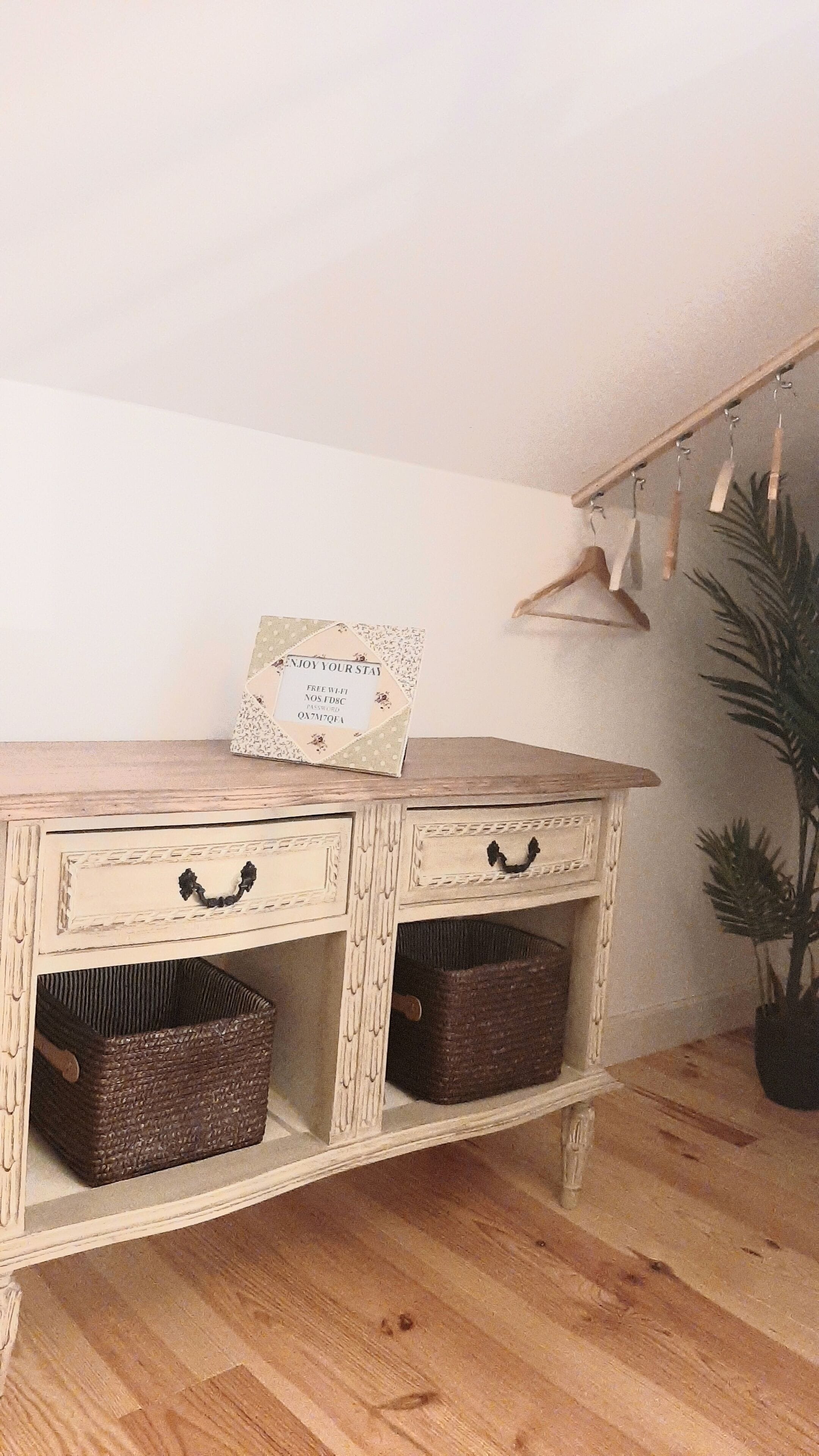 Eine Holzkommode mit Körben, ein Schild mit kostenlosem WLAN und eine Pflanze in der Ecke.