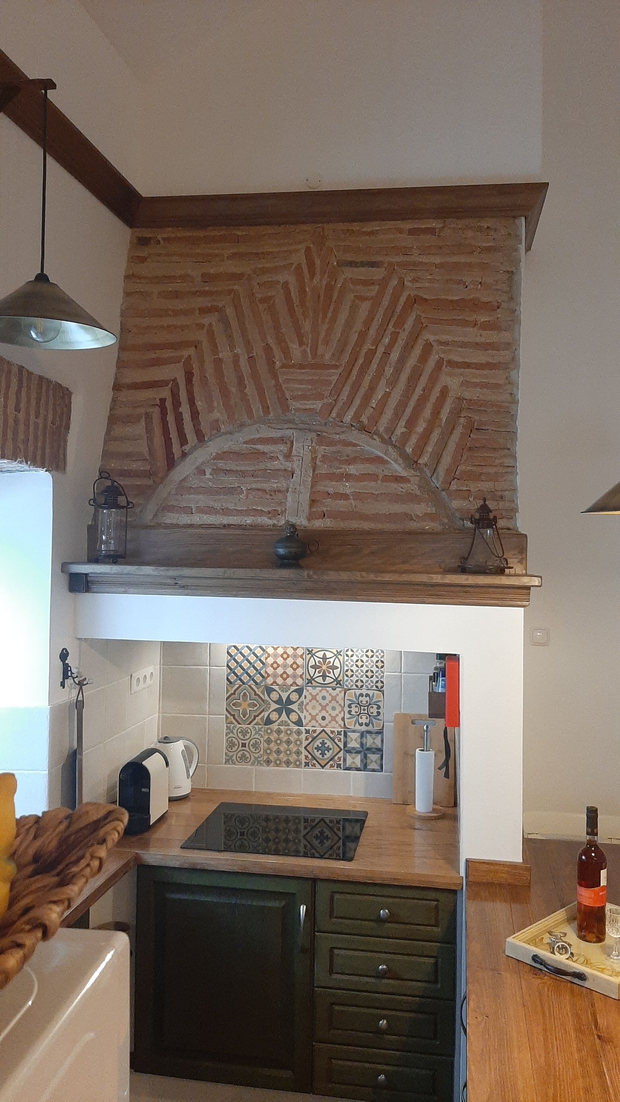 Eine Küche mit einer backsplash aus Ziegelsteinen, einer Holz Arbeitsplatte und einer hängenden Leuchte.