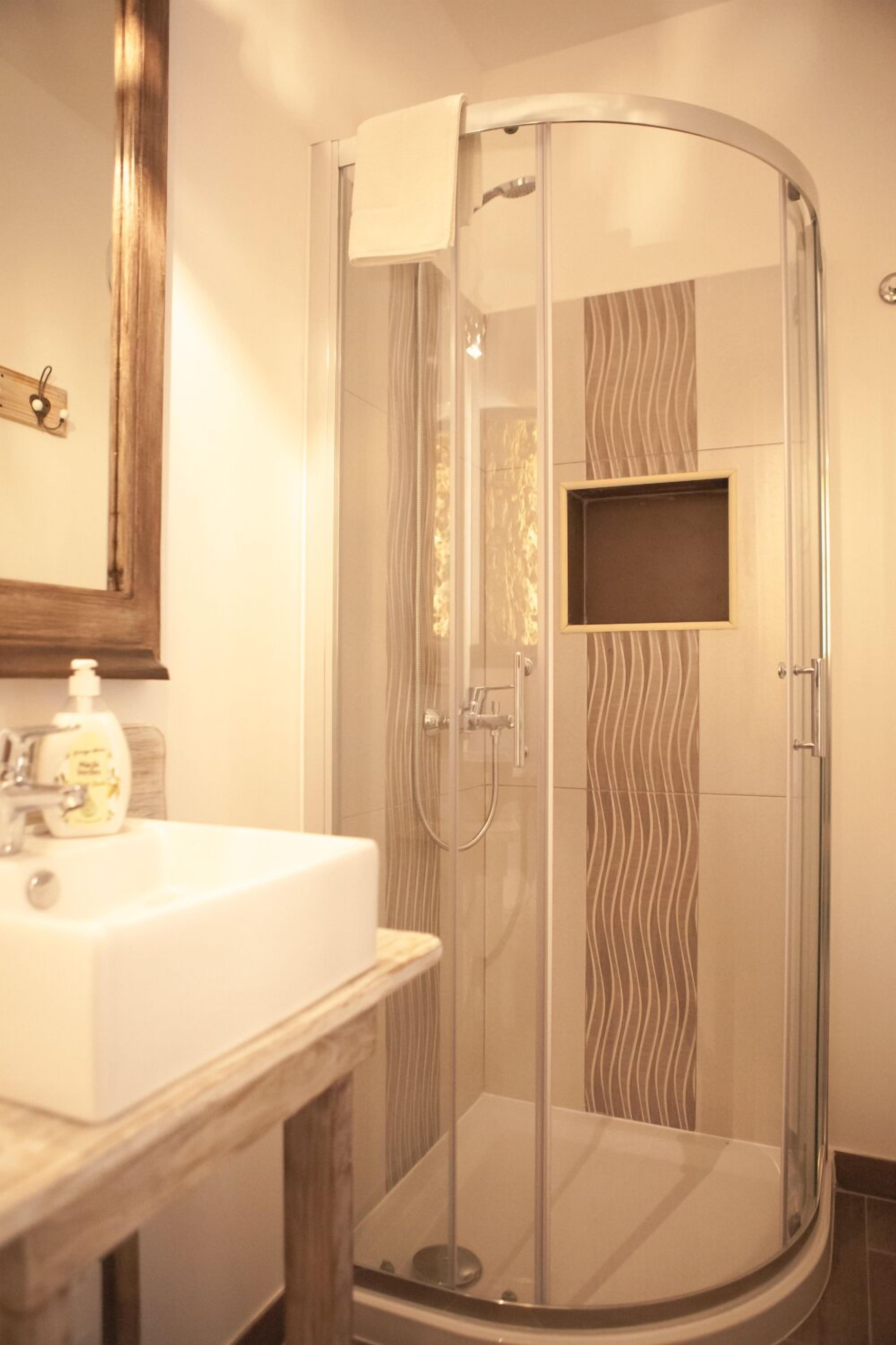 A modern bathroom with a glass-enclosed shower, a white sink, and a wooden vanity.