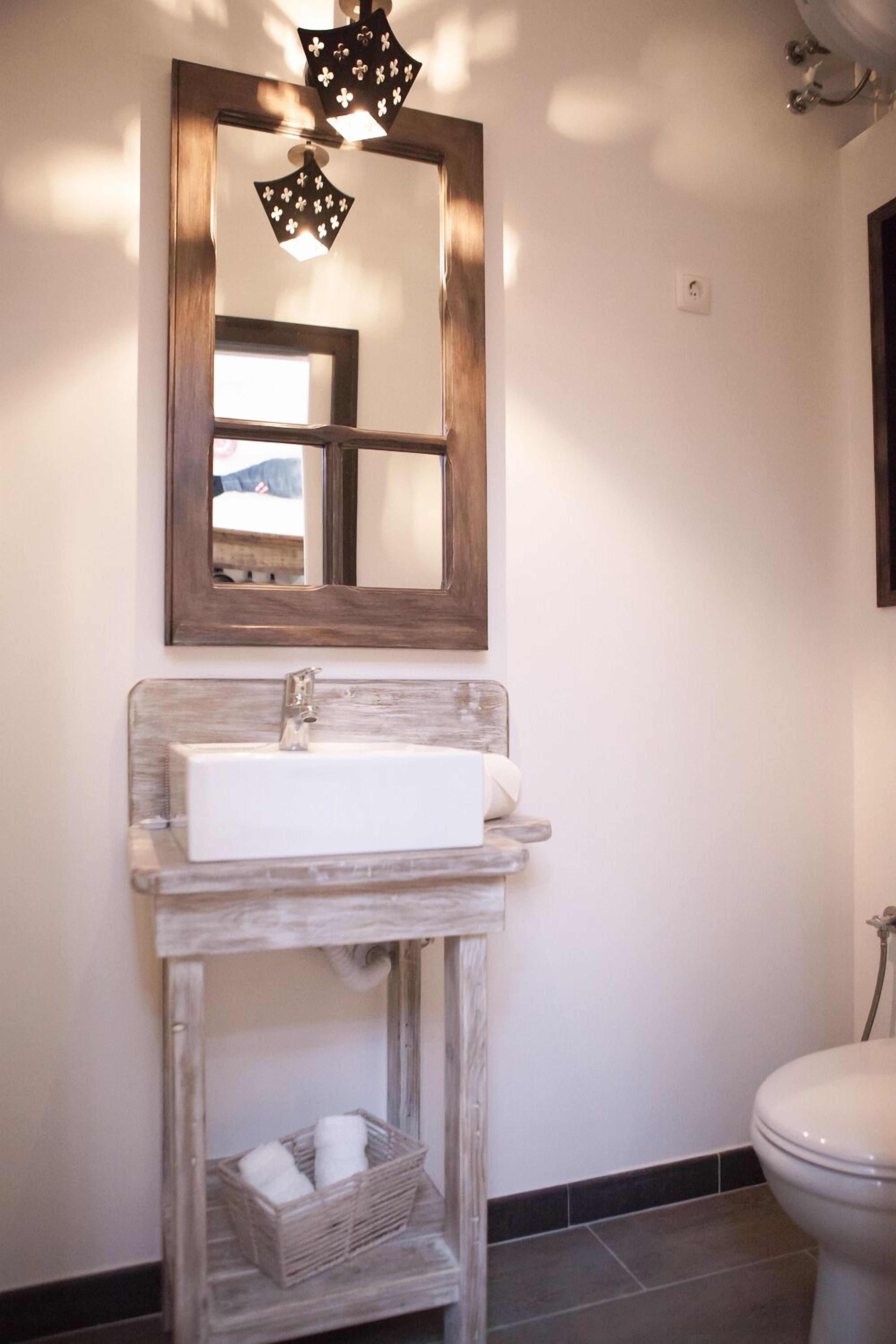 A bathroom with a wooden vanity, a mirror, and a toilet.