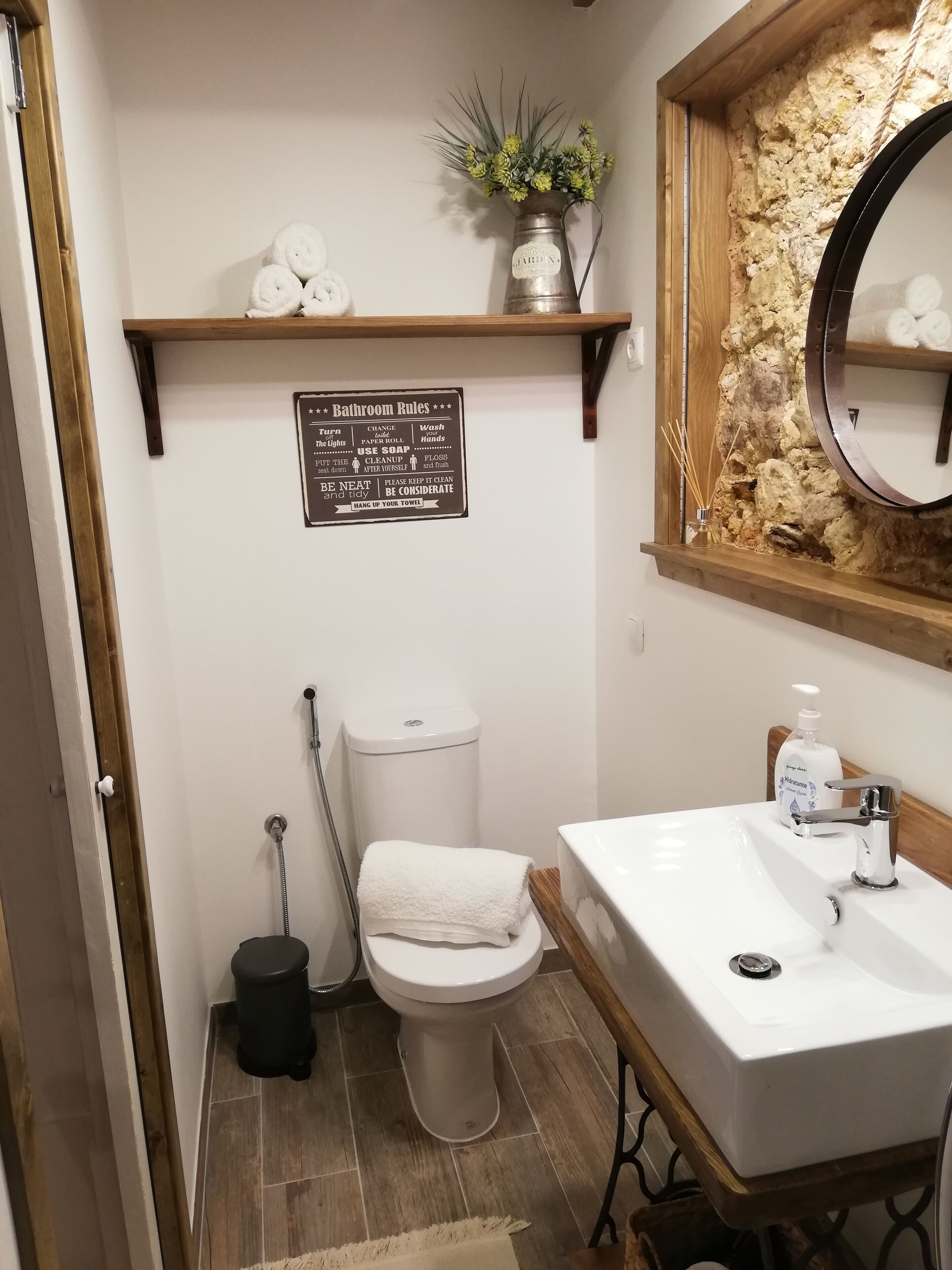 A bathroom with a toilet, sink, and a sign with bathroom rules.