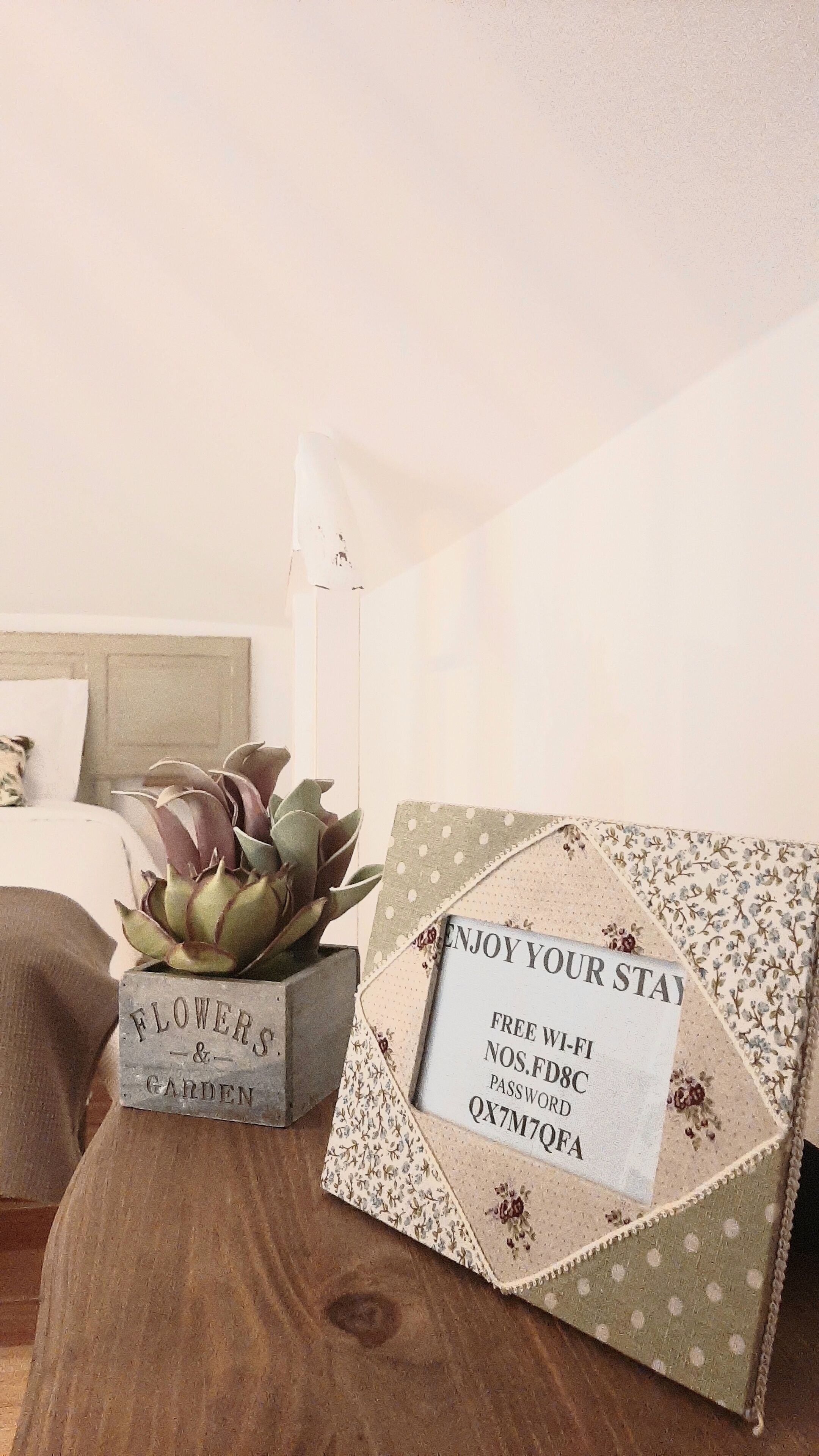 A wooden table with a decorative box labeled "FLOWERS & GARDEN" and a floral-patterned envelope with a free Wi-Fi password.