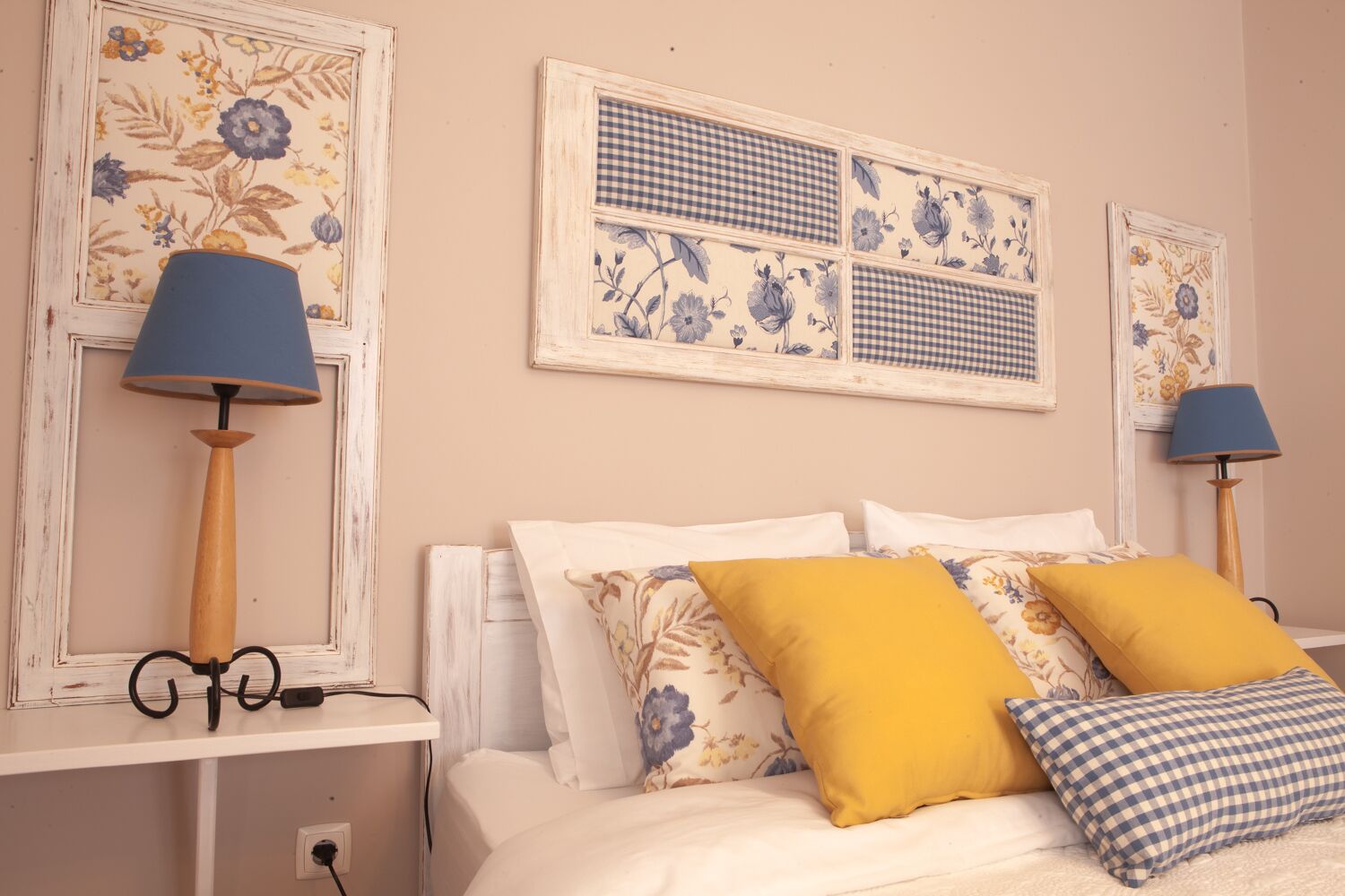 Een slaapkamer met een bed, twee lampen en wanddecoratie met bloemenprint.