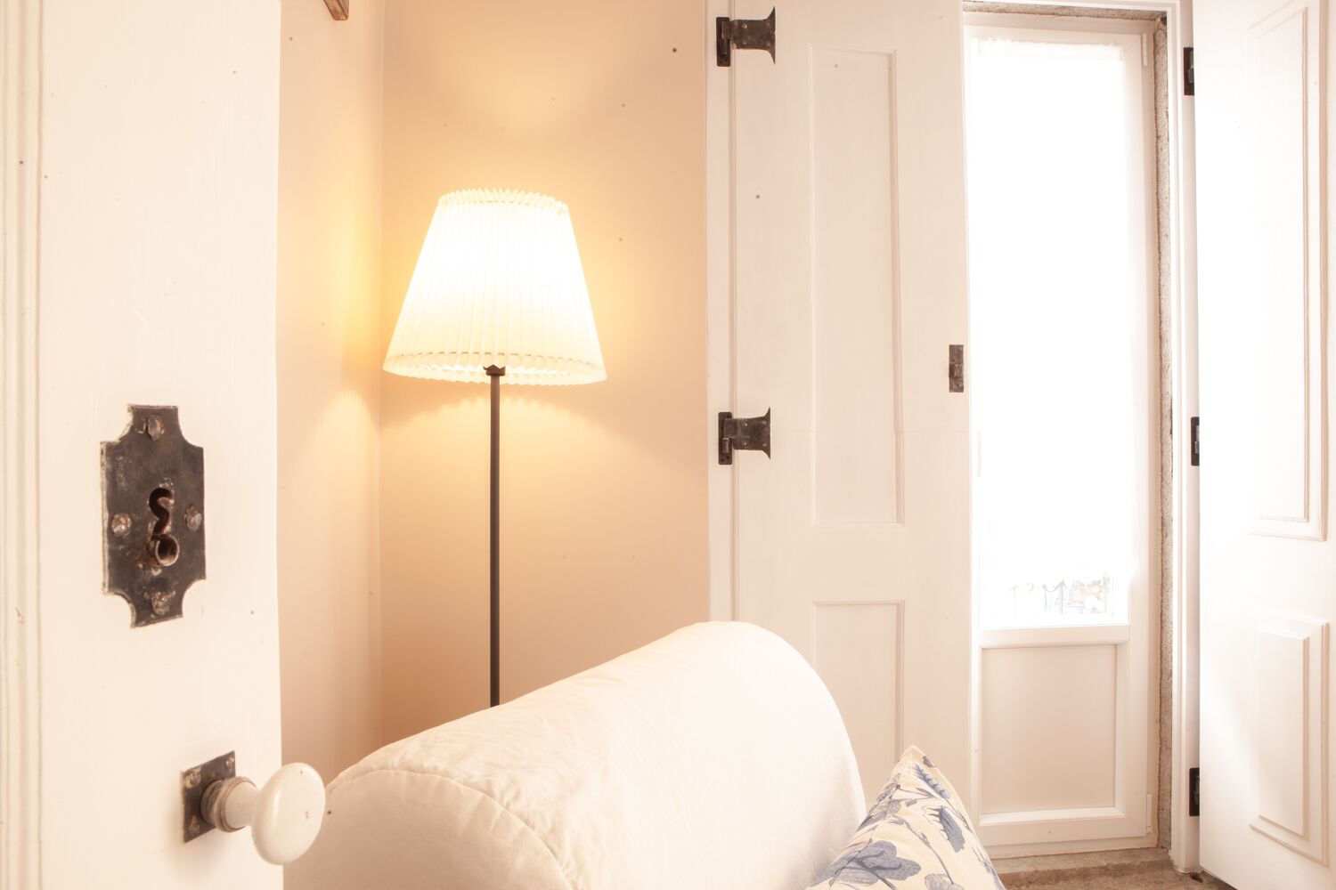 Een slaapkamer met een bed, een bedlamp en een deur.