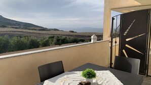 Un balcon avec une table, des chaises et une petite plante en pot.