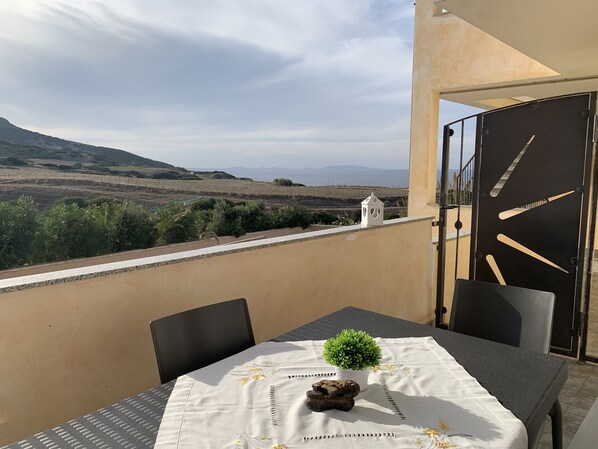 A balcony with a table, chairs, and a small potted plant.