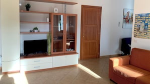 Un salon avec un téléviseur, un meuble en bois et un canapé.