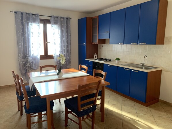 A kitchen with blue cabinets, a wooden dining table, and chairs.