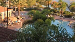 A resort with a swimming pool surrounded by palm trees and lounge chairs. - Lake View Penthouse Loft (Orlando)