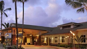 A hotel with a covered entrance, palm trees, and a stone fire feature. - Westin Princeville 2 Bedrooms Premium Unit  (Princeville)