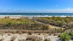 Une plage bordée d’une clôture en bois, offrant une vue dégagée sur l’océan.