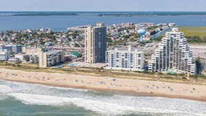 A coastal hotel with multiple high-rise buildings, a beach, and a view of the sea.