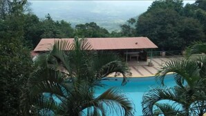 Un bâtiment doté d’un toit rouge, entouré d’une végétation luxuriante et d’une piscine.