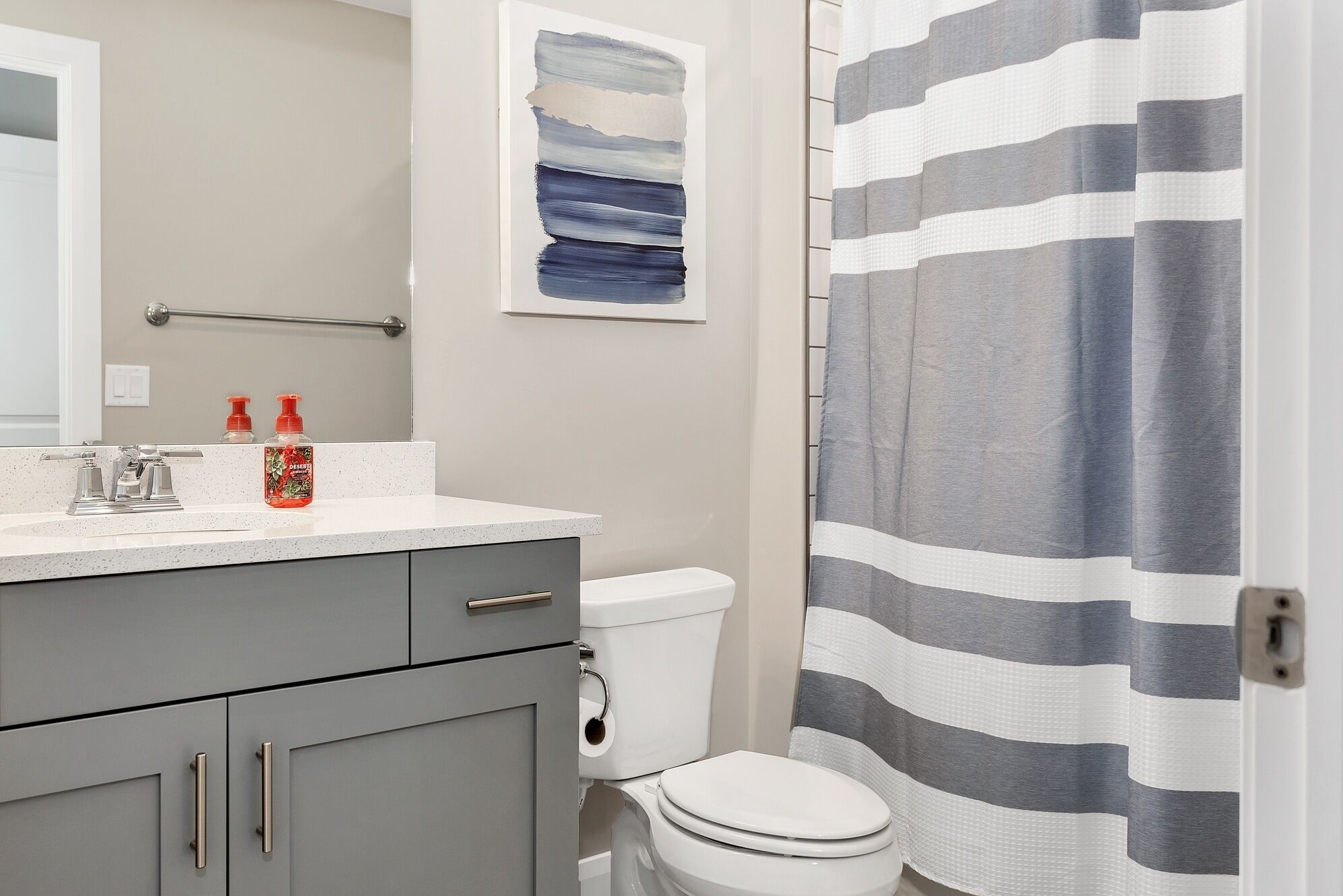 A bathroom with a white sink, a toilet, and a shower curtain with horizontal stripes.