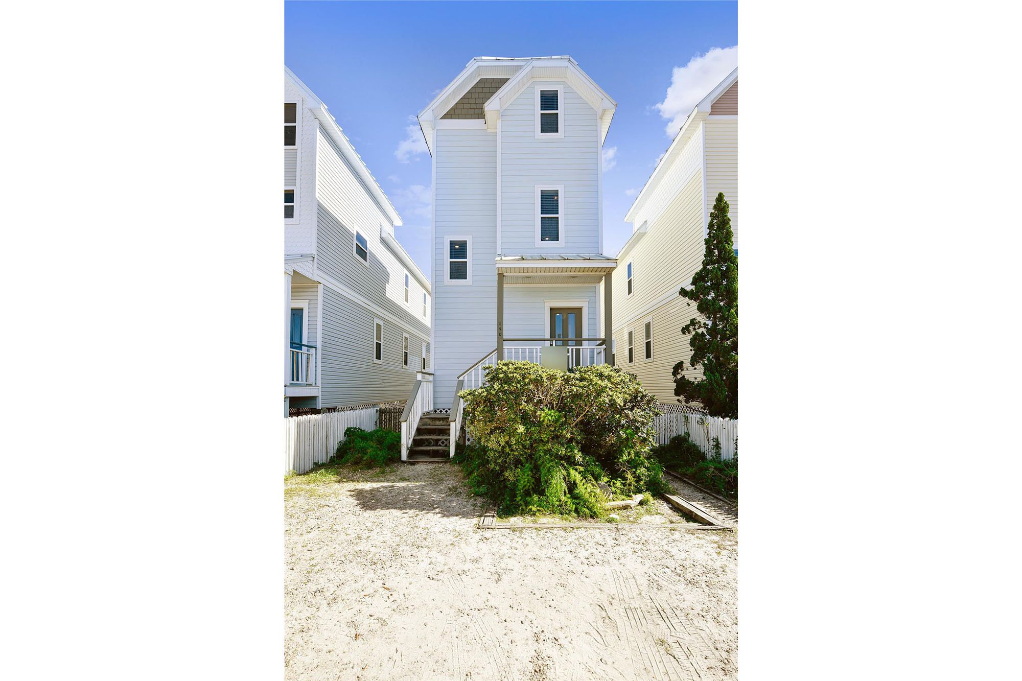 A row of white two-story houses with a central staircase leading to a front porch.