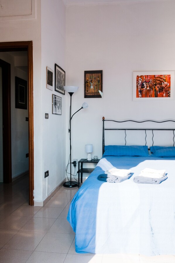 Une chambre à coucher avec un lit, une table de chevet, une lampe et un mur orné de tableaux.