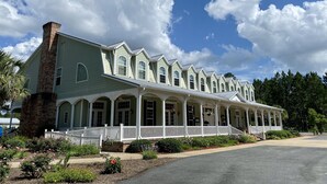 A large, multi-story building with a green facade and white railings, featuring multiple arched windows and a central chimney. - Blueberry Plantation Golf Resort (Alma)