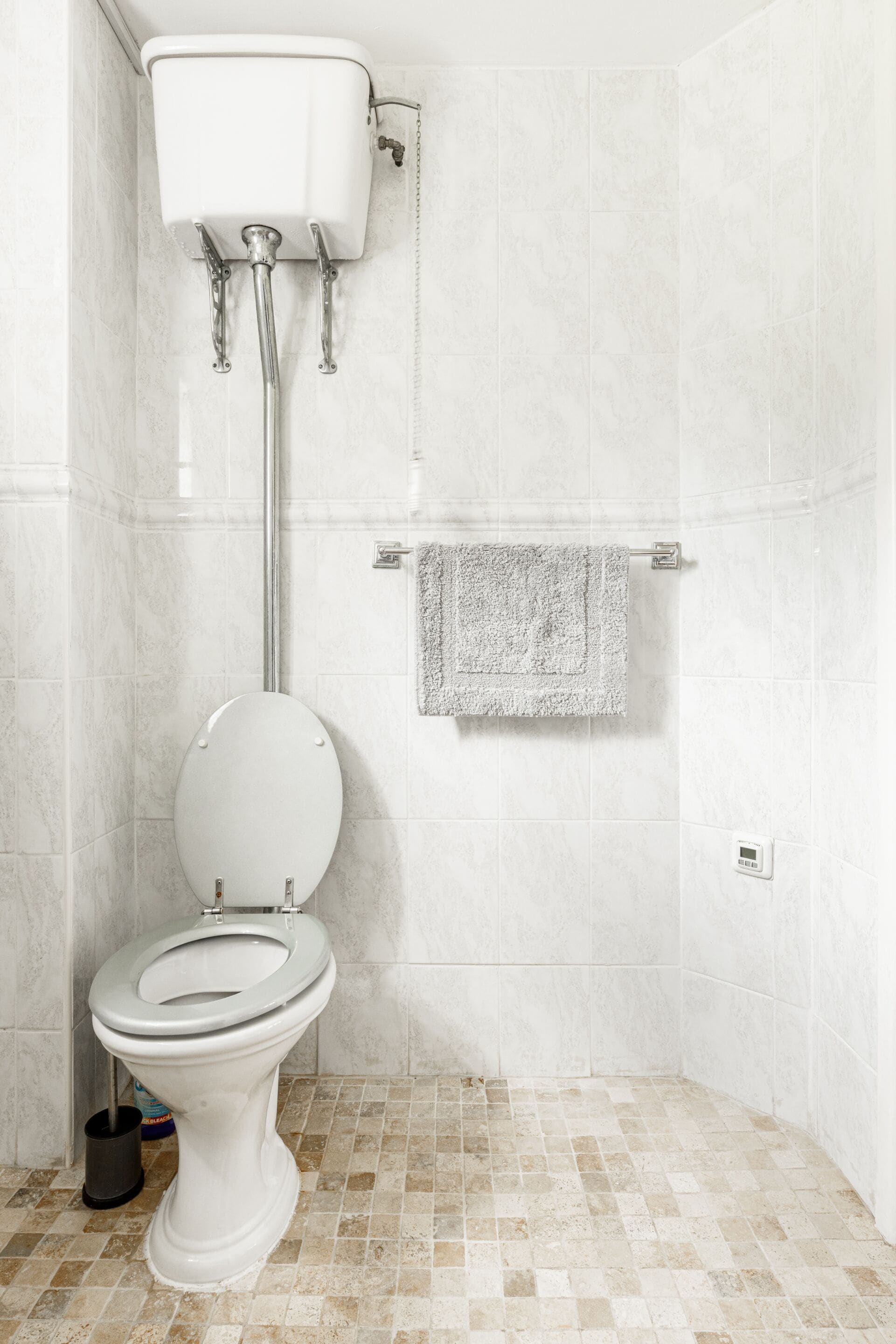 A bathroom with a toilet, a shower, and a towel rack.