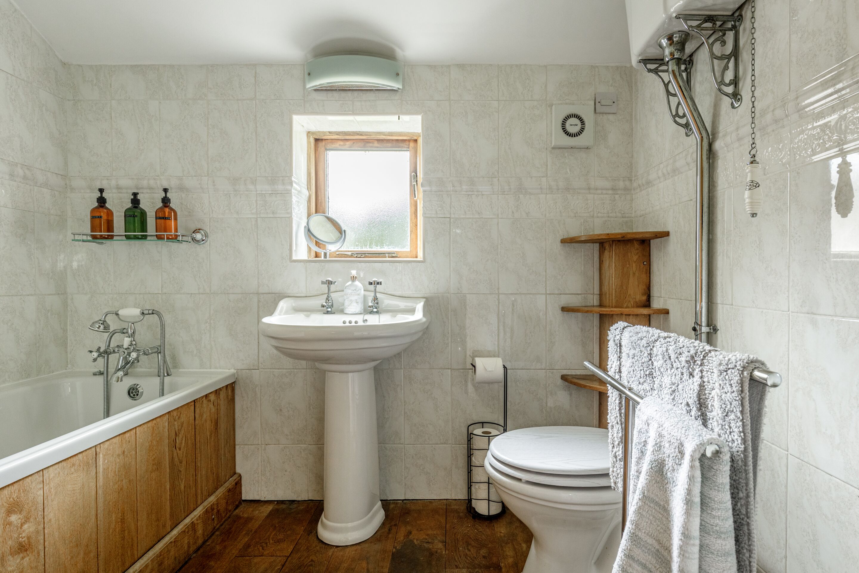 Une salle de bain avec une baignoire, un lavabo, des toilettes et une fenêtre.