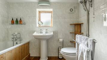 Une salle de bain avec une baignoire, un lavabo, des toilettes et une fenêtre.