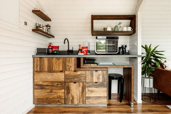 A compact kitchen with a built-in oven, a sink, and wooden cabinetry. - Oak Mead (Wrexham)