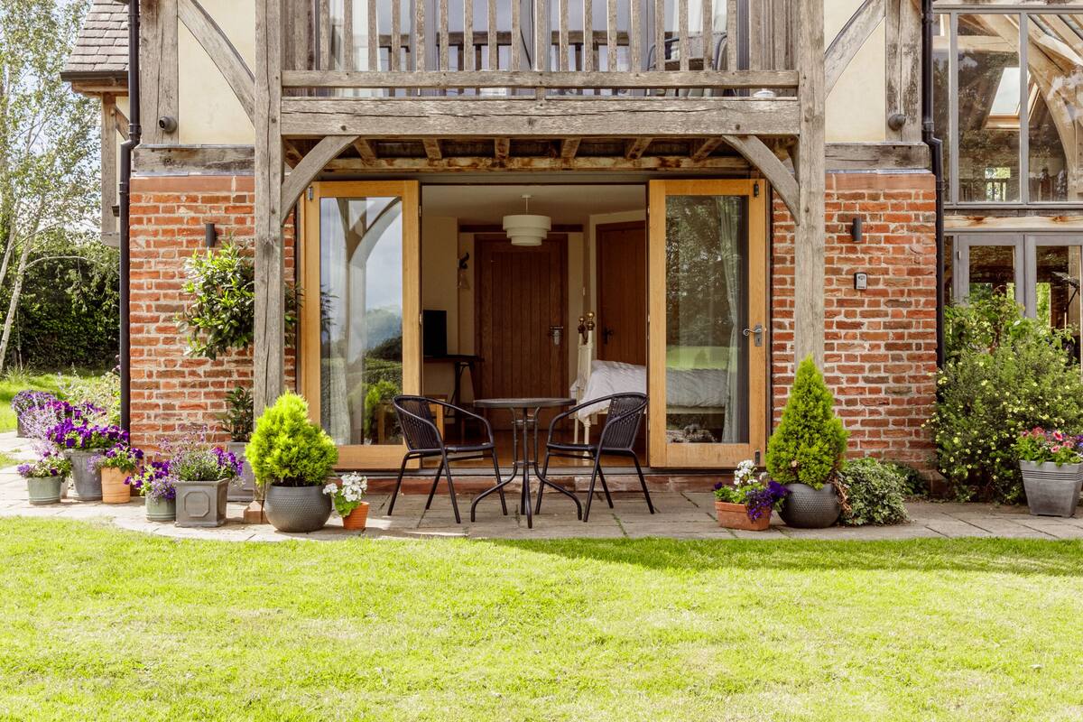 A two-story house with a balcony, large windows, and a garden.