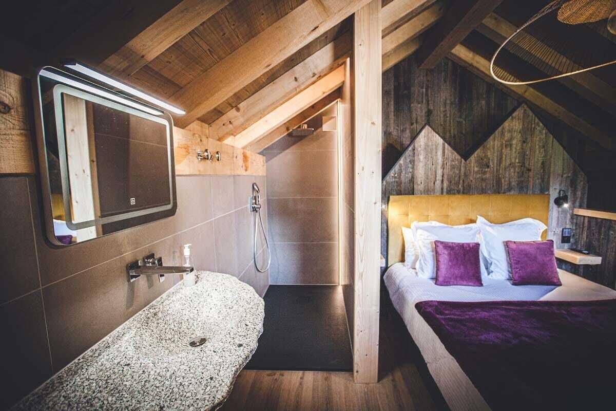 A modern bathroom with a freestanding bathtub, a shower, and a bed with a headboard.