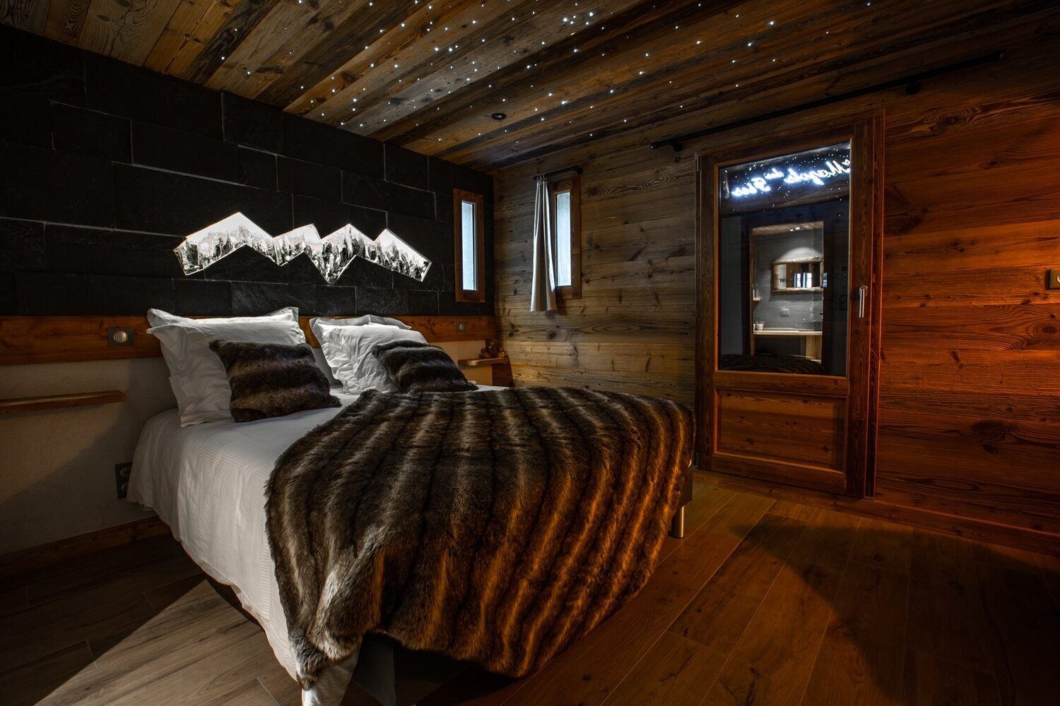 Ein gemütliches Schlafzimmer mit Bett, Holzwänden, einer Wand aus Stein und einem kleinen Fenster.