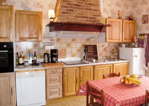 Una cocina con gabinetes de madera, una estufa, una cafetera y una mesa con fruta.