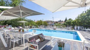 Un espace aménagé au bord de la piscine, avec des chaises longues, une table et des parasols.
