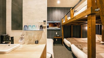 A hotel room with a wooden bunk bed, a bathroom with a sink and mirror, and a television on the wall.