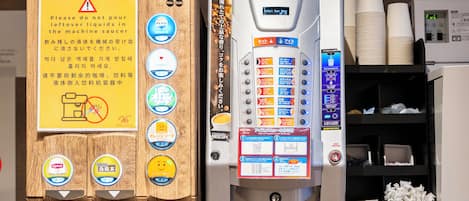 Une machine à café offrant plusieurs options de boissons et munie d’un avertissement indiquant qu’il ne faut pas verser les liquides restants dans la machine.