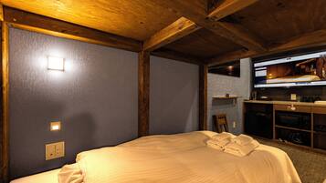A hotel room with a bed, a television, and a small kitchenette.