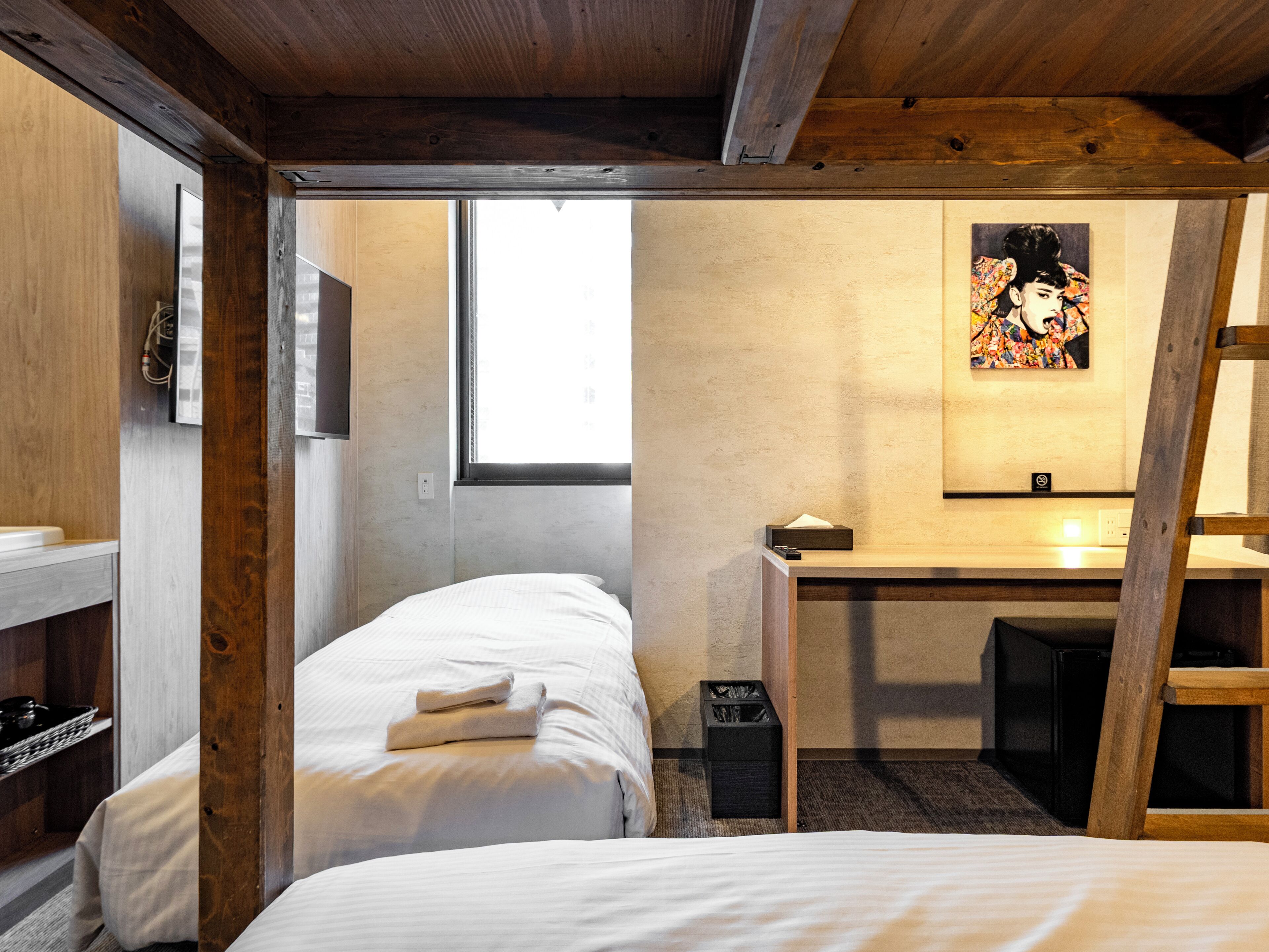 A bedroom with a bed, a desk, and a window.