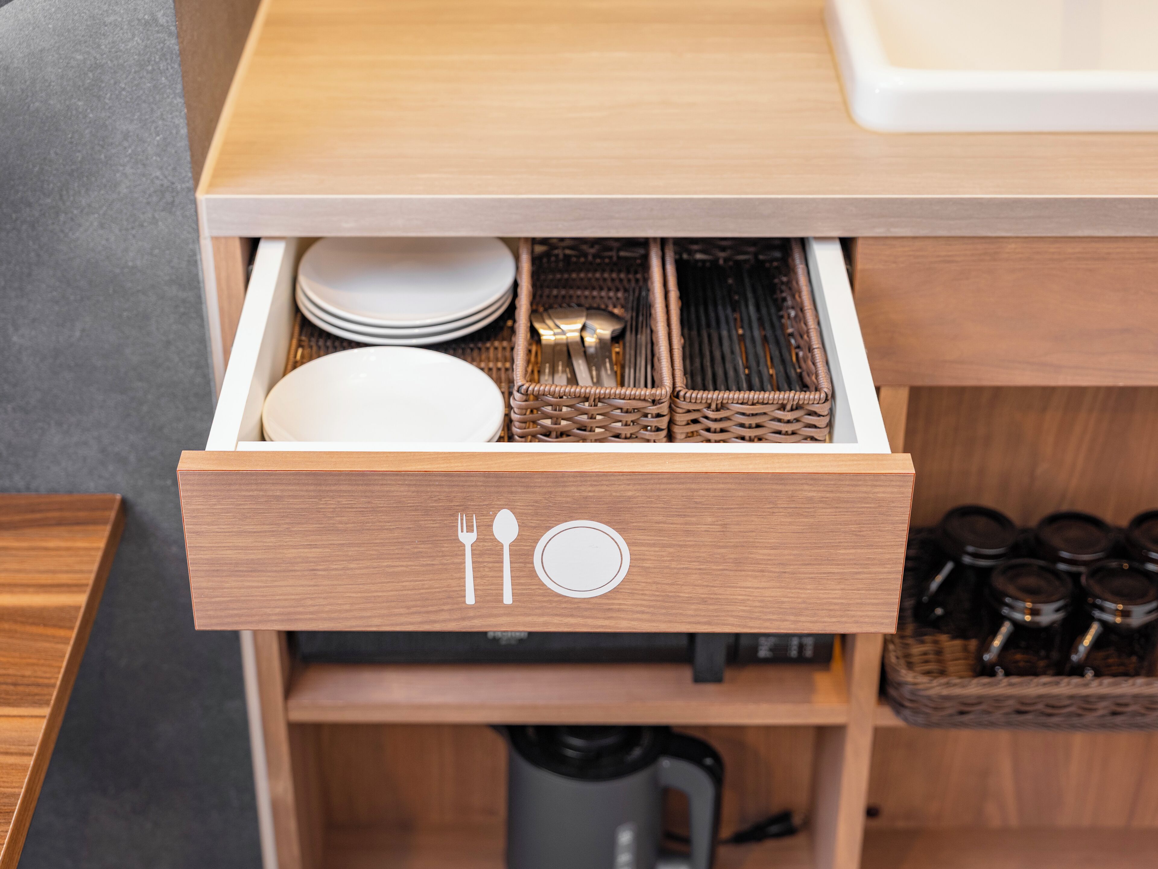 A kitchen drawer with utensils and plates.