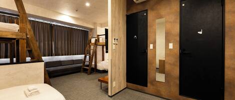 A room with bunk beds, a ladder, a sofa, a door, and an air conditioning unit.
