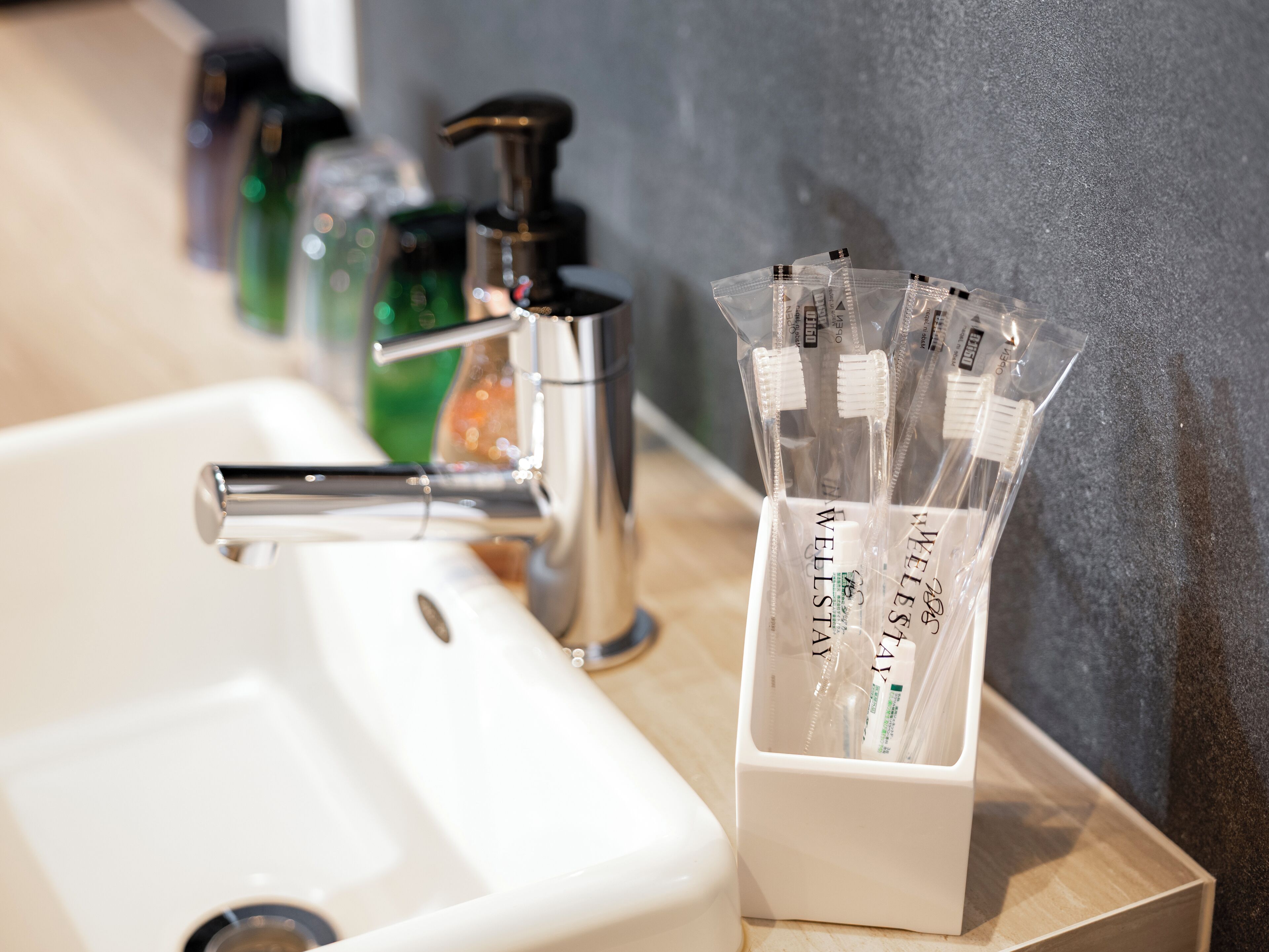 A bathroom sink with a chrome faucet, a soap dispenser, and a toothbrush holder with multiple toothbrushes.