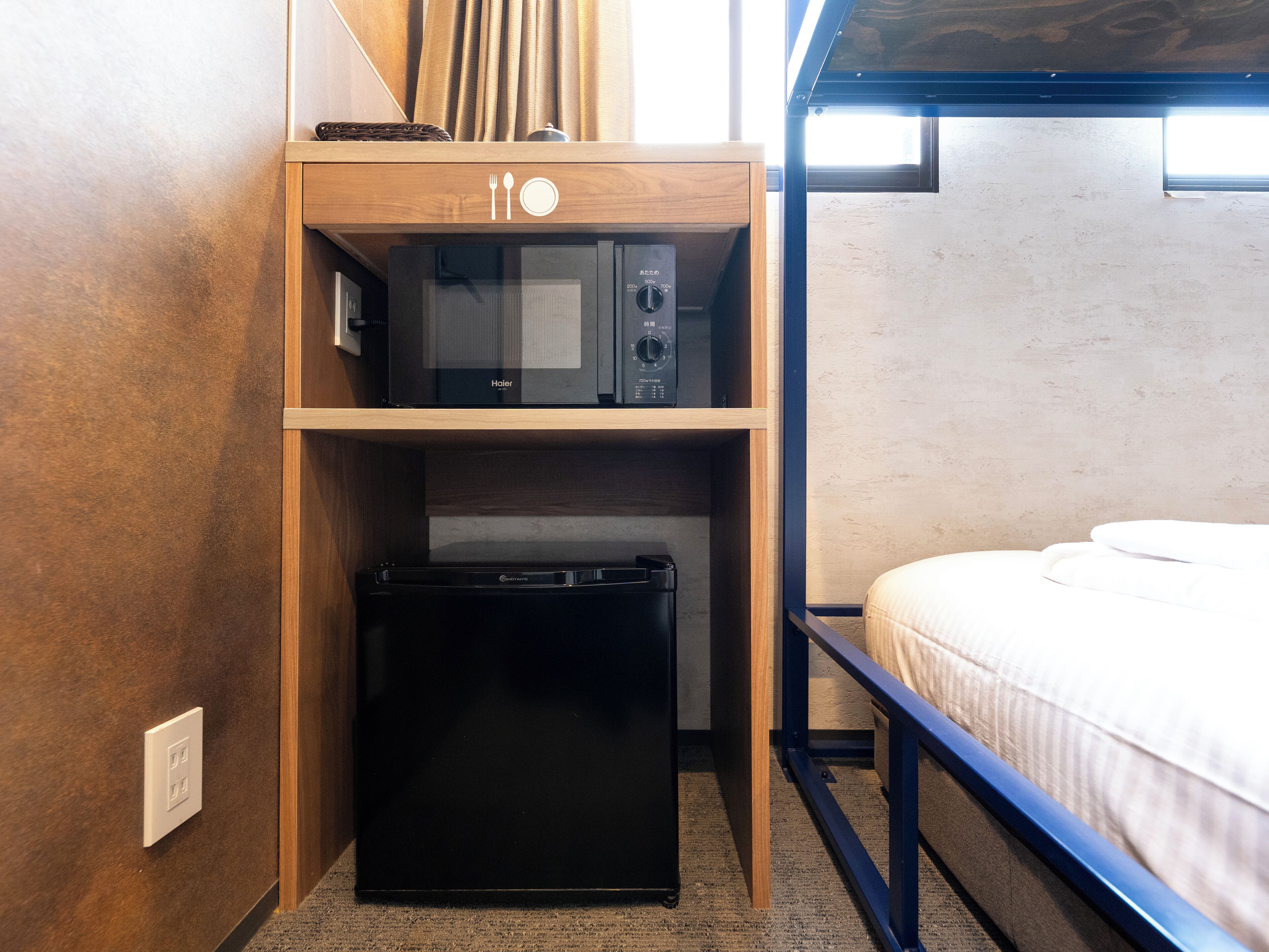 Habitación pequeña con literas, microondas y refrigerador.
