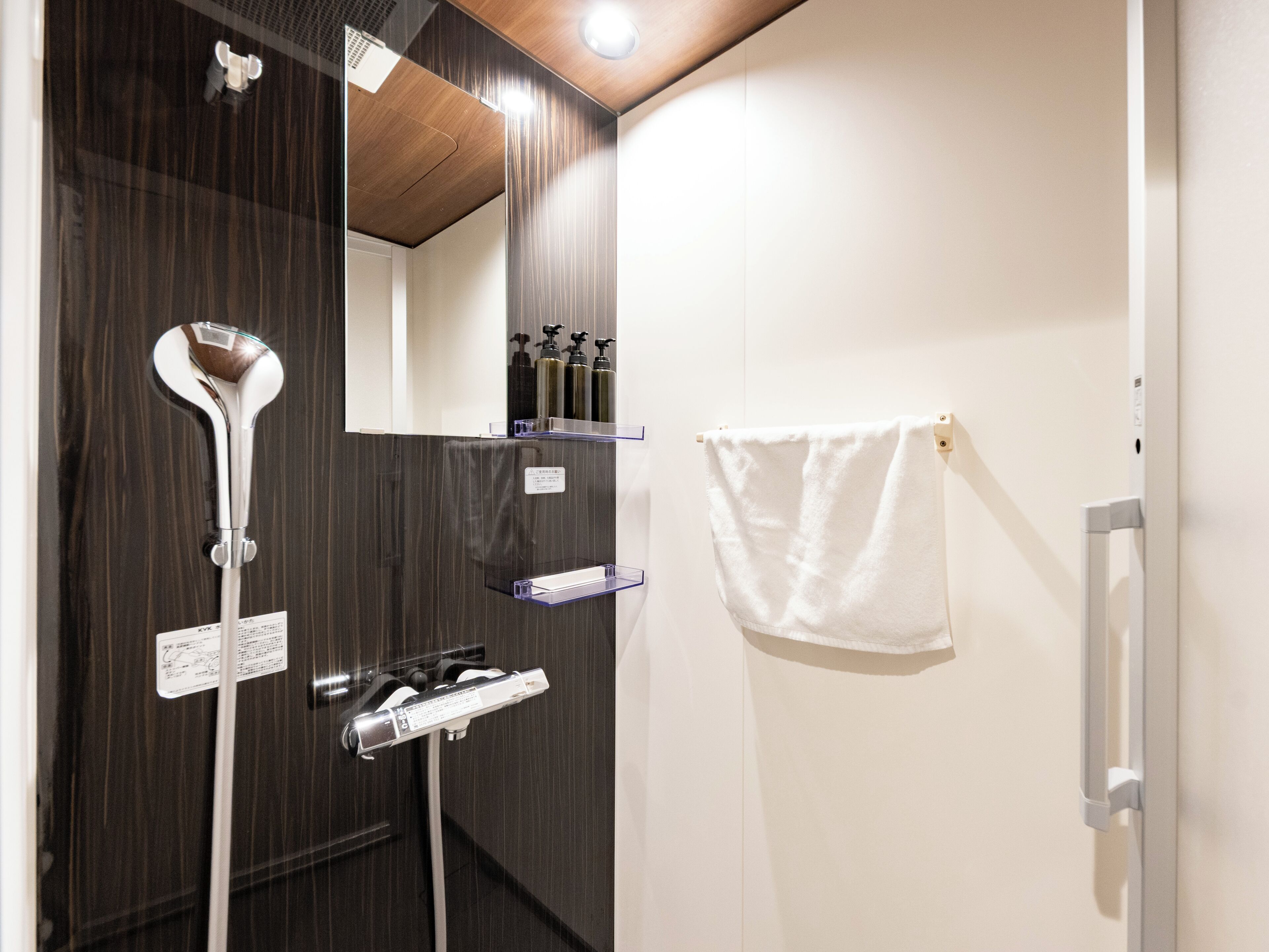 Ein modernes Badezimmer mit Holzpaneelen, einem Spiegel, einem Handtuchhalter und einem Ablagefach für Toilettenartikel.